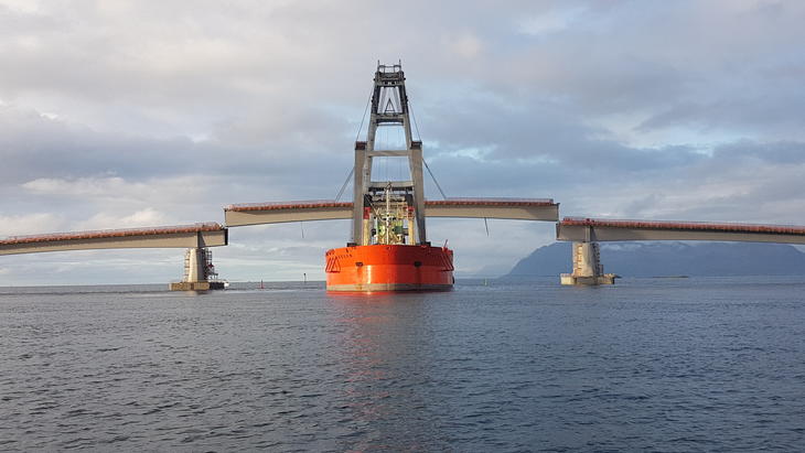 Stor kran-båt heiser på plass midtseksjonen av Sandsøy-broen.